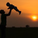 Happy dad throws the baby at sunset